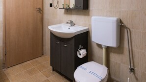 Une salle de bain comprenant des toilettes, un lavabo, un meuble et un miroir.