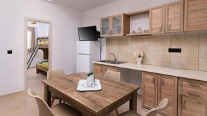 Une cuisine compacte avec des meubles en bois, un téléviseur encastré et un petit coin repas comprenant une table et des chaises.