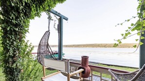 Una terrazza in legno con una poltrona a dondolo, una panca e un vaso rustico.