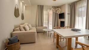 A modern living room with a sofa, a dining table, and a TV mounted on the wall. - PAPADRIA VILLAS as featured in THE TIMES - Modern Luxury Getaway nr Kathisma (Tsoukalades)