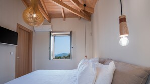 A bedroom with a bed, a window, a wooden ceiling, and a hanging light fixture. - PAPADRIA VILLAS as featured in THE TIMES - Modern Luxury Getaway nr Kathisma (Tsoukalades)