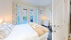 A bedroom with a bed, a dresser, and a door. - Stunning SEAVIEW Coastal Cottage - Sleeping 8 in 4 Bedrooms - Pool and Beach Access Included. (Filey)
