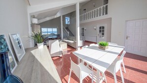 A spacious living area with a dining table, white furniture, and a view of the sea through large windows. - HOUSE ON THE BEACH, FOZ (Unknown)