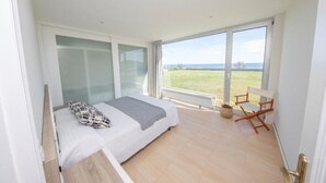 A bedroom with a bed, a chair, and a view of the sea. - HOUSE ON THE BEACH, FOZ (Unknown)