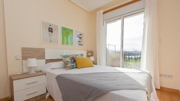 Un dormitorio con cama, mesita de noche, cómoda y ventana con vistas.