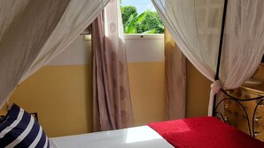 Un lit avec une literie blanche et rouge, un oreiller à rayures et une moustiquaire.