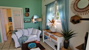 Un salon avec un canapé blanc, une console en bois, une plante en pot et un miroir au mur.