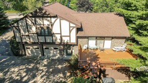 A two-story house with a garage, a deck with outdoor furniture, and a small garden area.
