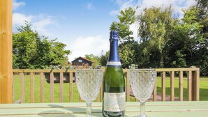Una botella de cava Waitrose sobre una mesa de madera con dos copas de vino.
