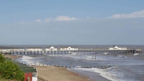 Un muelle con varios edificios blancos, una playa de arena y el océano.