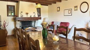 A dining area with a wooden table, chairs, a fireplace, and hanging lights. - House with pool in the Luberon for 6 people (Saint-Saturnin-lès-Apt)