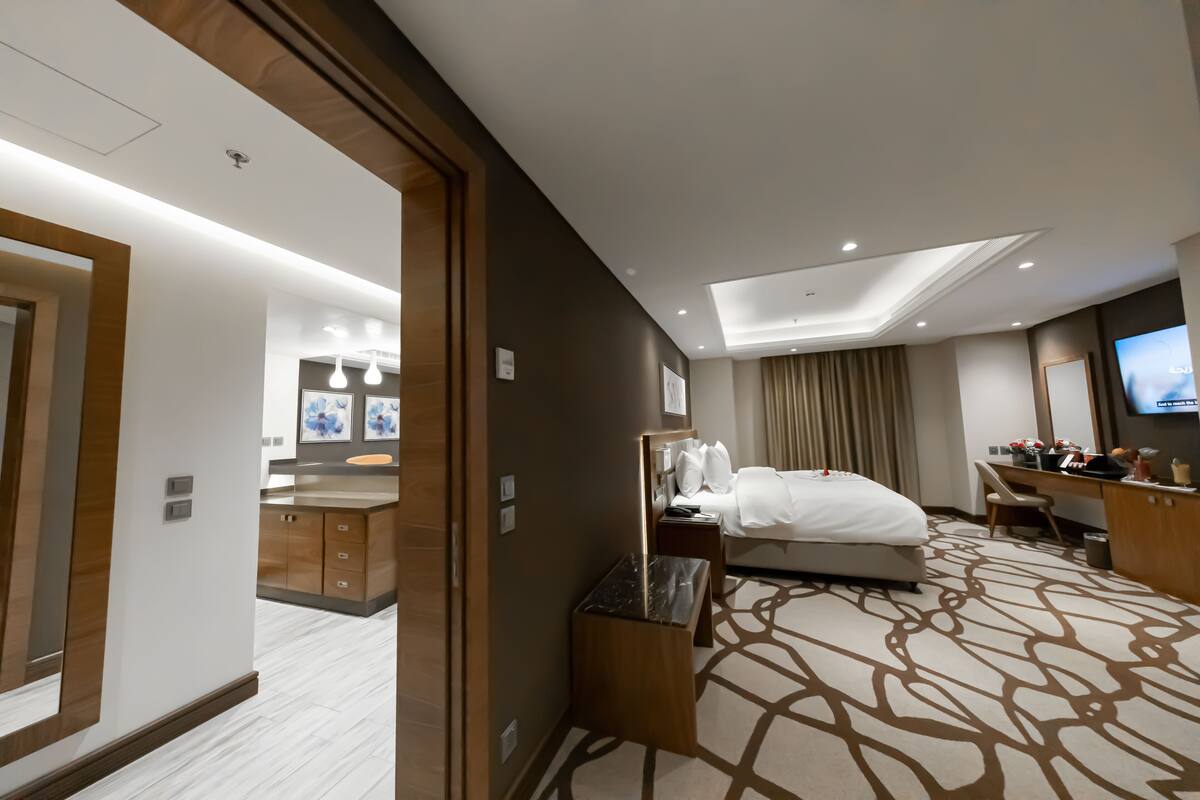 A hotel room with a bed, desk, and a television.