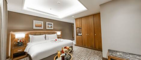 A hotel room with a large bed, a bedside table with a lamp, a small table with a vase, and a wardrobe.