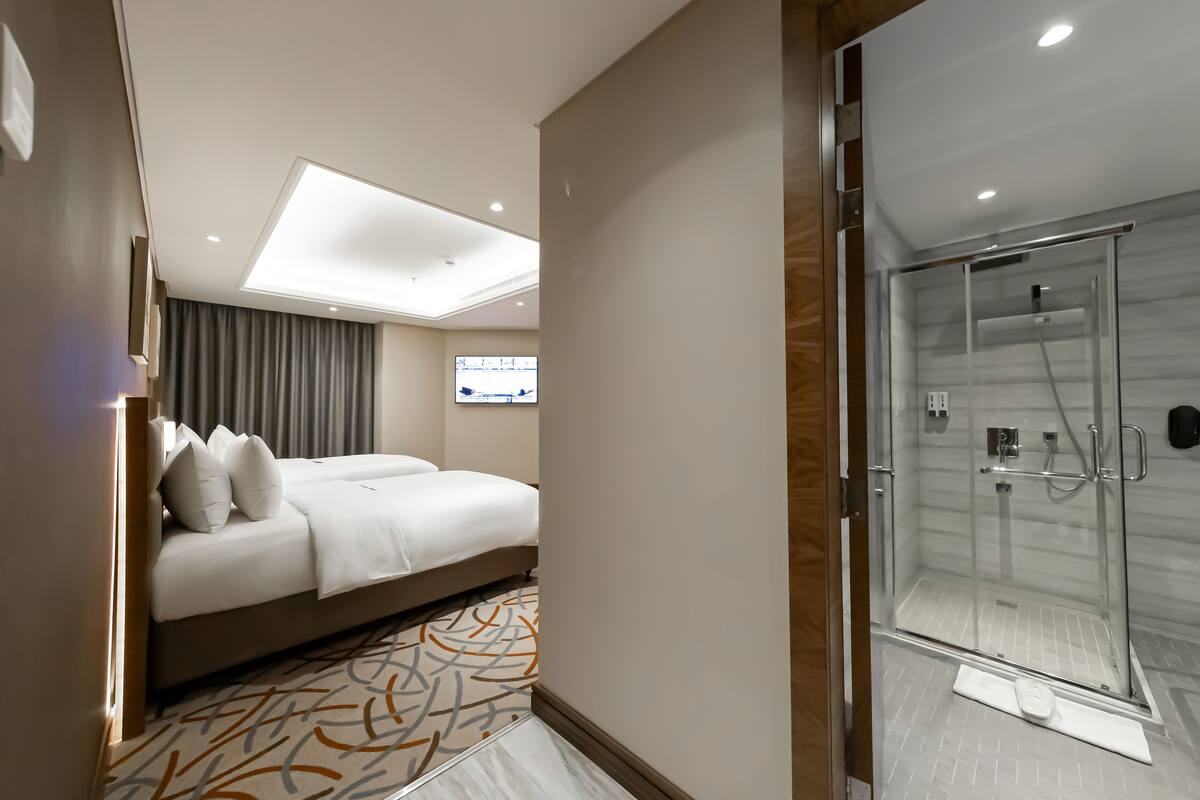 A hotel room with a bed, a shower, and a view of the outside.