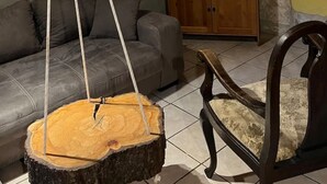 Una sala de estar con techo de madera, televisor, sofá, mueble de madera y una silla colgante.