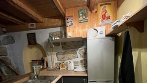 Una cocina compacta con techo de madera, lavamanos integrado, refrigerador y salpicadero de pared de piedra.
