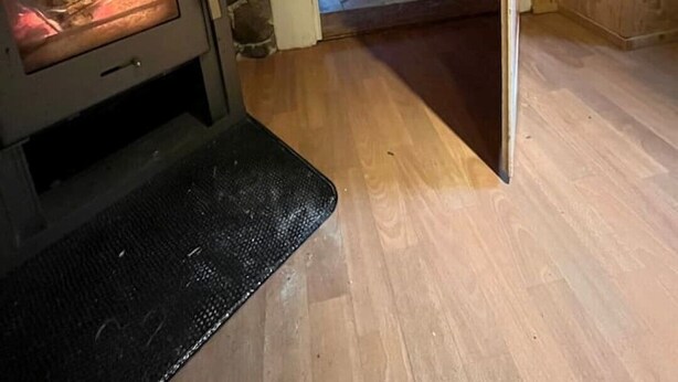 Una habitación acogedora con una estufa de leña, una cama y un ventanal pequeño.