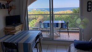 Un balcon avec une table, des chaises et un ventilateur.