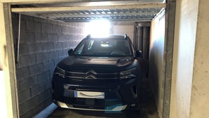 Un véhicule se trouve à l’intérieur d’un garage dont le sol est en béton et les murs en métal.