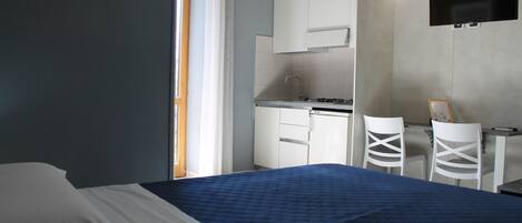 Un dormitorio con cama, escritorio y kitchenette.