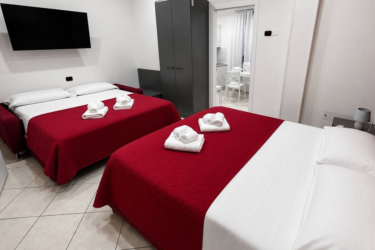 A hotel room with two beds, a TV, a wardrobe, and a bathroom.