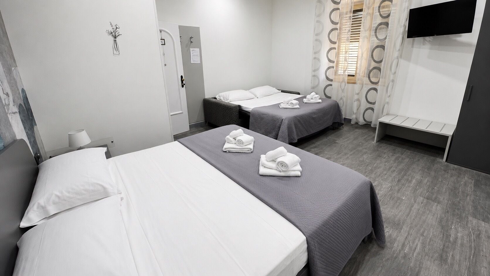 A hotel room with two beds, a flat-screen TV, and a small seating area.