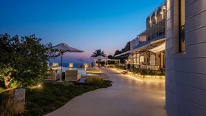 Un hotel moderno con zona de piscina, asientos al aire libre y vistas al océano.