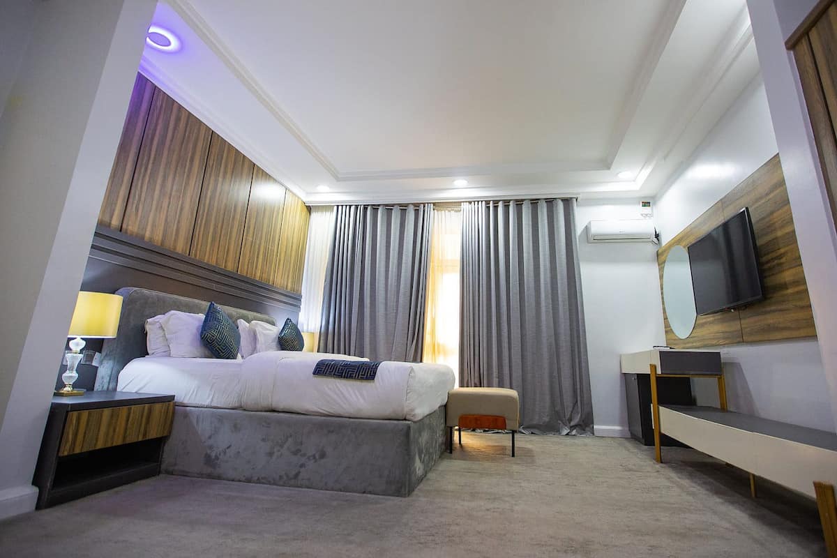 A modern hotel room with a bed, bedside table, lamp, and a TV.