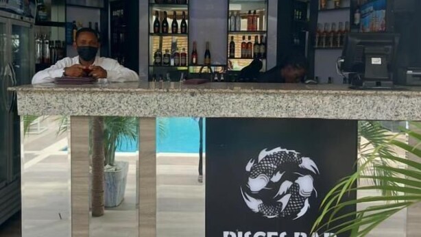 A bar with a sign reading "PISCES BAR" and shelves of bottles behind the counter. - Prosbel Hotel (Abuja)