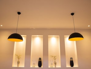 A modern interior with pendant lights and rectangular shelves displaying vases and decorative items. - Prosbel Hotel (Abuja)