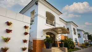 A two-story house with a white exterior, a balcony, and a covered entrance. - Prosbel Hotel (Abuja)