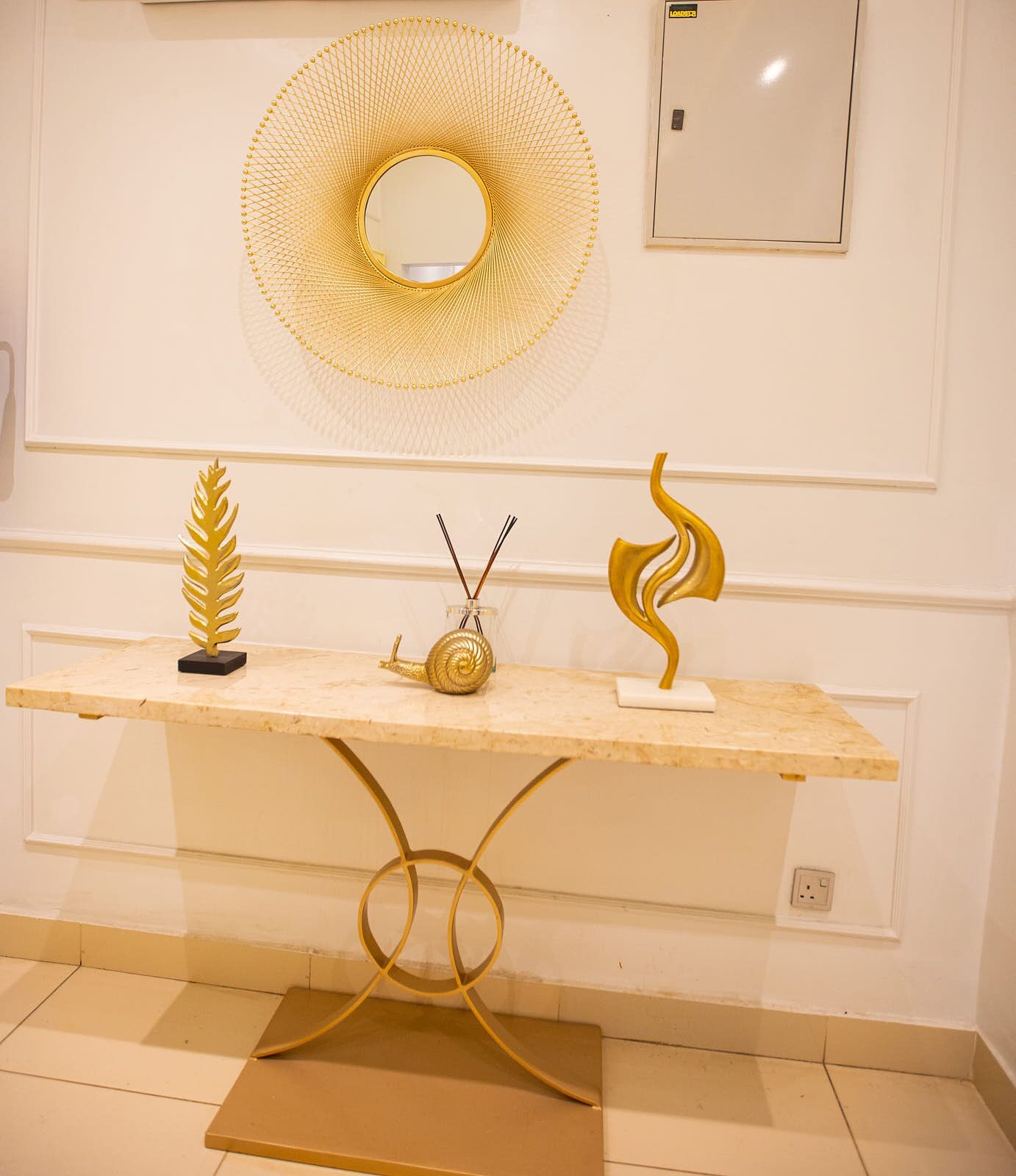 Un bancone di marmo con tre elementi decorativi dorati: una foglia, una lumaca e una scultura a forma di fiamma.