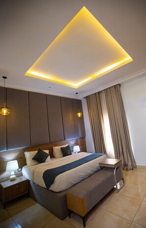 A modern hotel room with a large bed, bedside tables, and a ceiling light fixture. - Prosbel Hotel (Abuja)