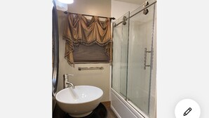 A bathroom with a glass shower enclosure, a white sink, and a vanity with a mirror.