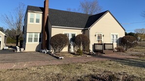 A two-story house with a brick chimney, a front porch, and a well-maintained lawn.