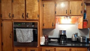 A kitchen with wooden cabinets, a built-in oven, a coffee maker, and a toaster.