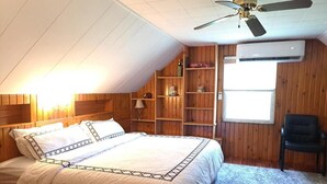 A bedroom with a bed, wooden shelving, a ceiling fan, and an air conditioning unit.
