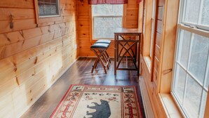 A wooden cabin interior with a bench, a table, and a rug with a bear design. - Book now to get your free ticket to Dollywood, Anakeesta, and other venues! (Sevierville)