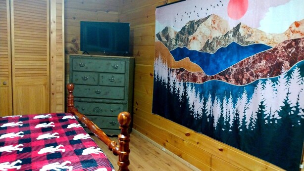 A room with a bed, a dresser, and a painting of a mountain landscape. - Book now to get your free ticket to Dollywood, Anakeesta, and other venues! (Sevierville)