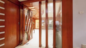 Ein Korridor mit Holztüren, einer Glastrennwand und einer Treppe, die in ein Obergeschoss führt.