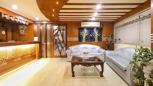 Eine Hotelhalle mit einer Rezeption, zwei Sofas, einem Couchtisch und einer Dekoration an der Wand.
