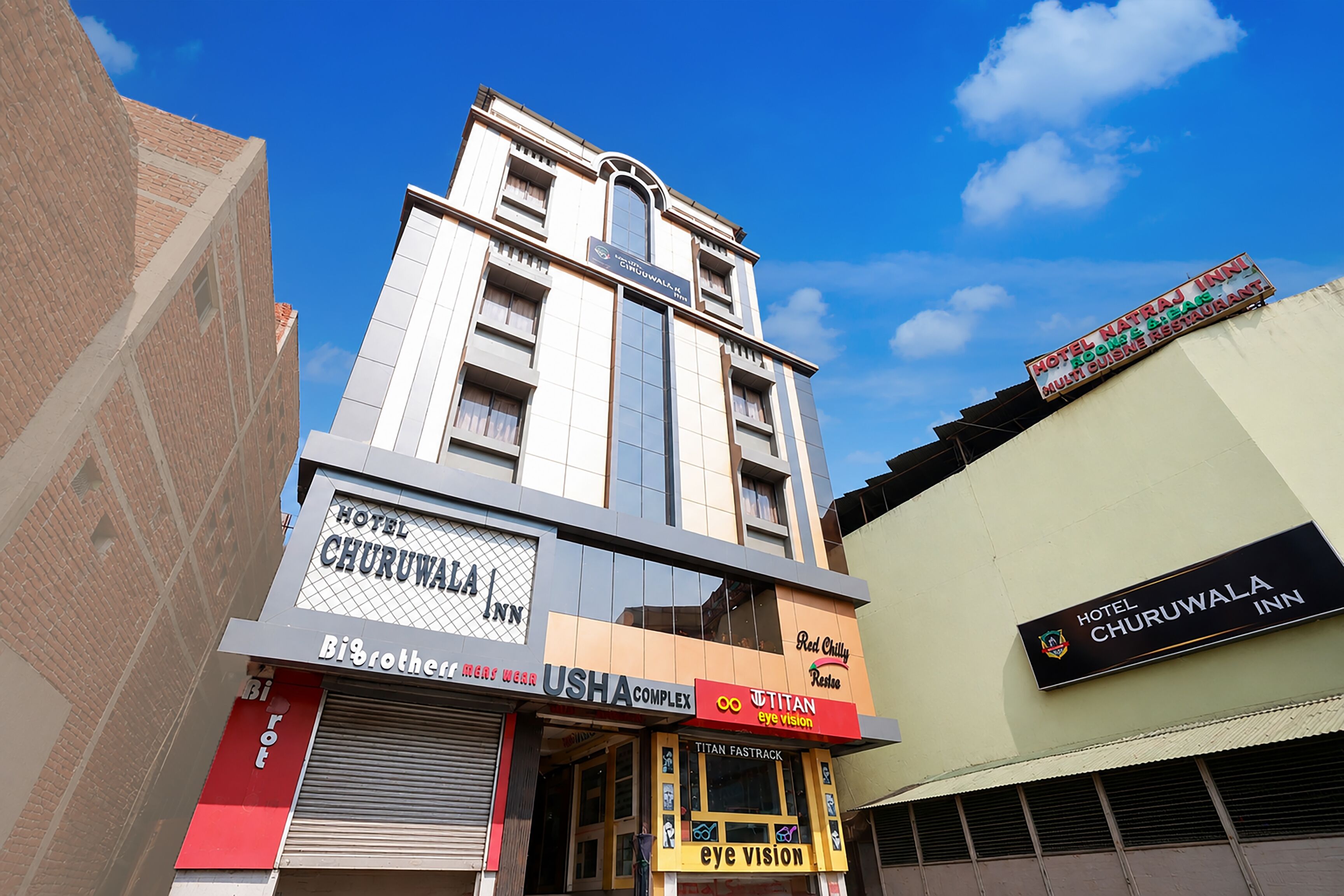 A hotel named 'Hotel Churuwala Inn' with a signboard, a visible entrance, and a clear blue sky in the background.