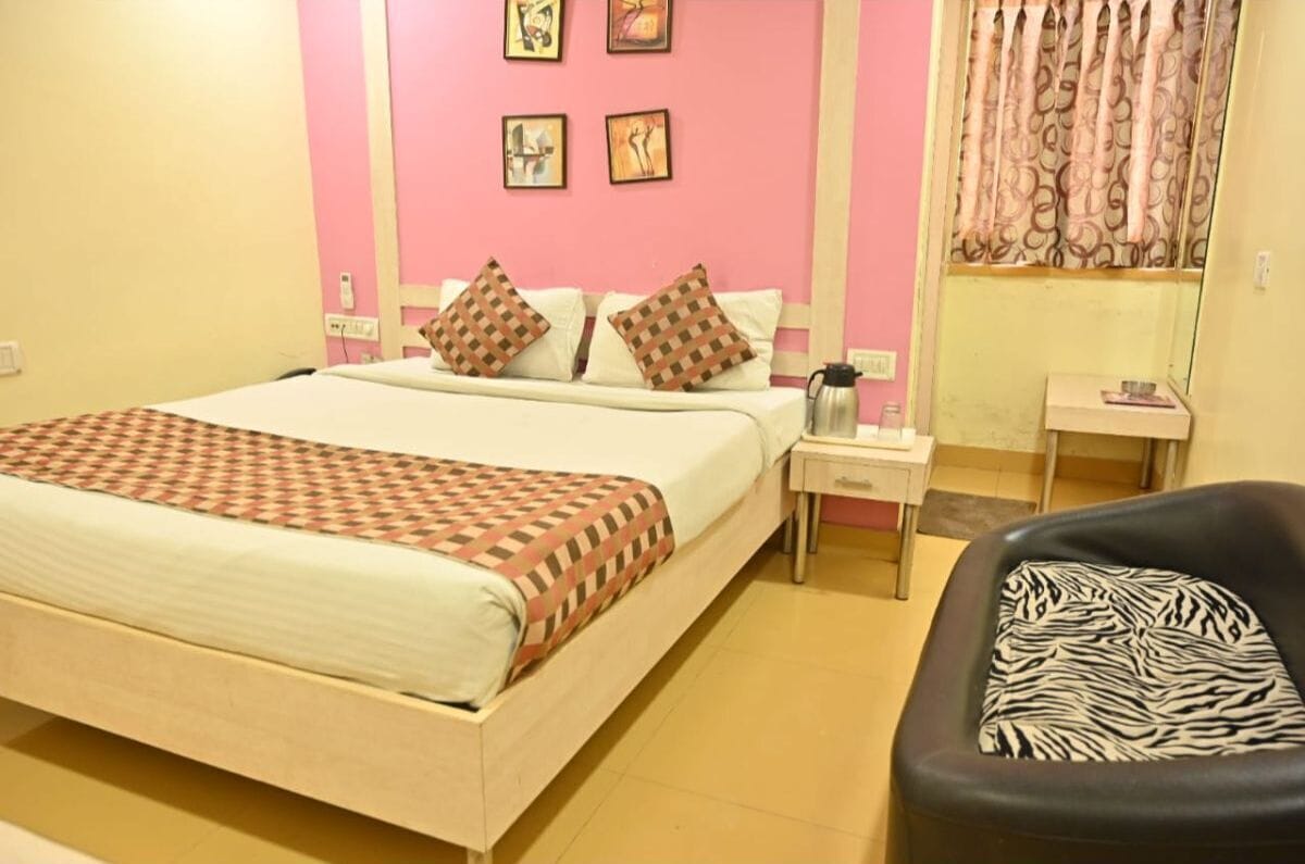 A bedroom with a bed, pillows, a nightstand, a chair, and a window with curtains.