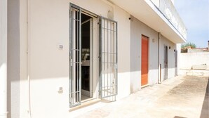 A building with a gated entrance, a red door, and a tiled patio area. - 2 bedroom cozy home in Torre Chianca - Lecce (Torre Chianca - Lecce)