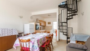 A compact living space with a dining area, kitchen, and a spiral staircase. - 2 bedroom cozy home in Torre Chianca - Lecce (Torre Chianca - Lecce)