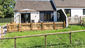 A two-story house with a fenced backyard, a patio with outdoor furniture, and a small garden area.