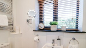 A bathroom with a toilet, sink, and window with blinds.