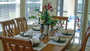Un coin repas avec une table en bois, dressée pour quatre personnes, entourée de chaises.