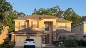 Une maison à deux étages avec un garage, une allée et une voiture garée dans le garage.