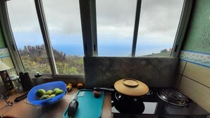 Cuina amb una finestra gran, una taula de tallar blava, una cuina i un bol amb fruita.
